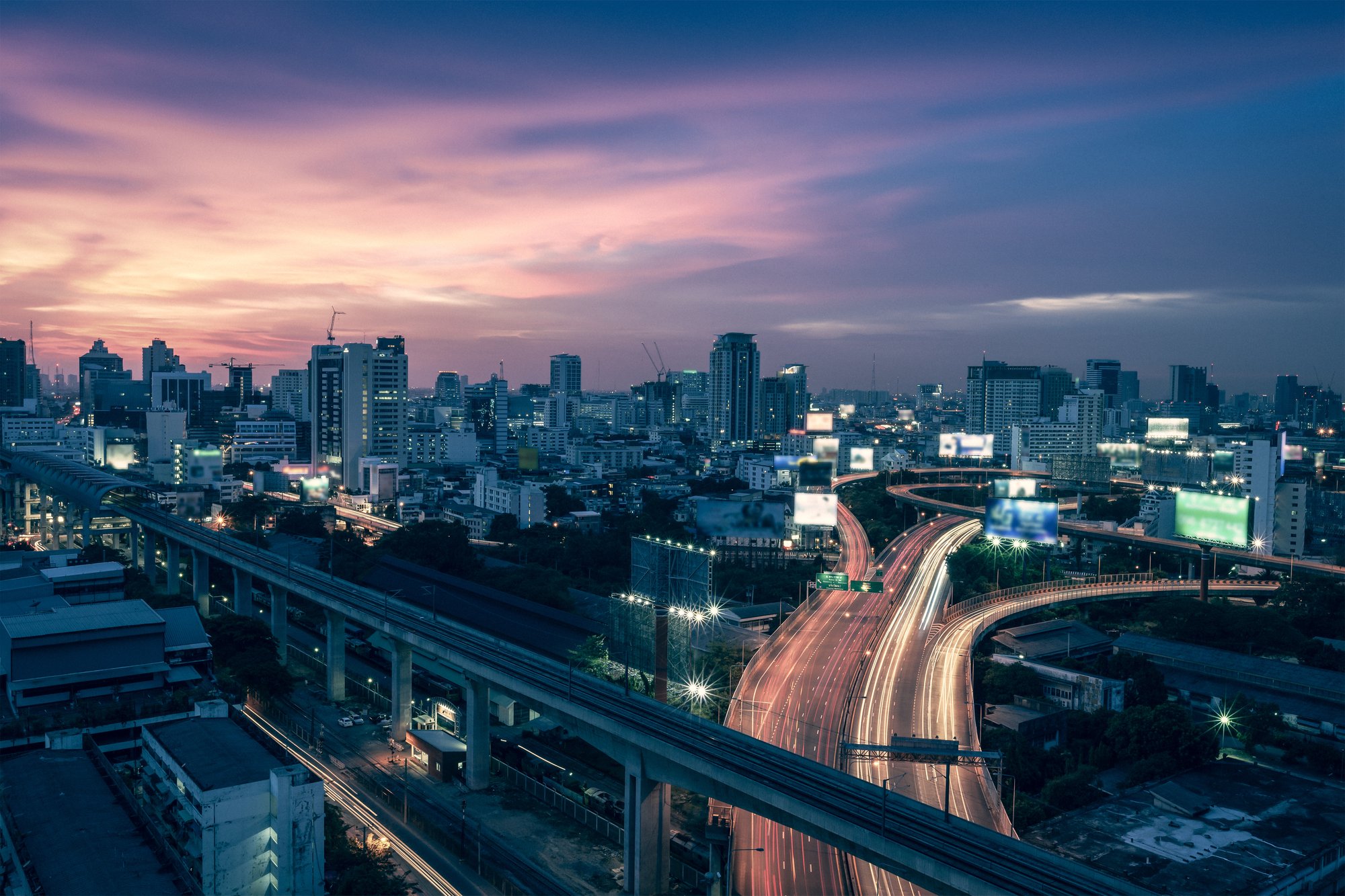 Panoramica di una smart city. Si vedono in lontananza i grattacieli e in primo piano delle strade interconnesse con display lungo la strada.